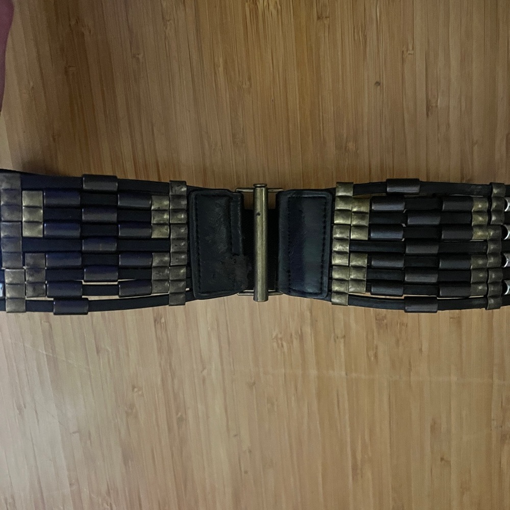 Textured black and gold belt with small rip in front
